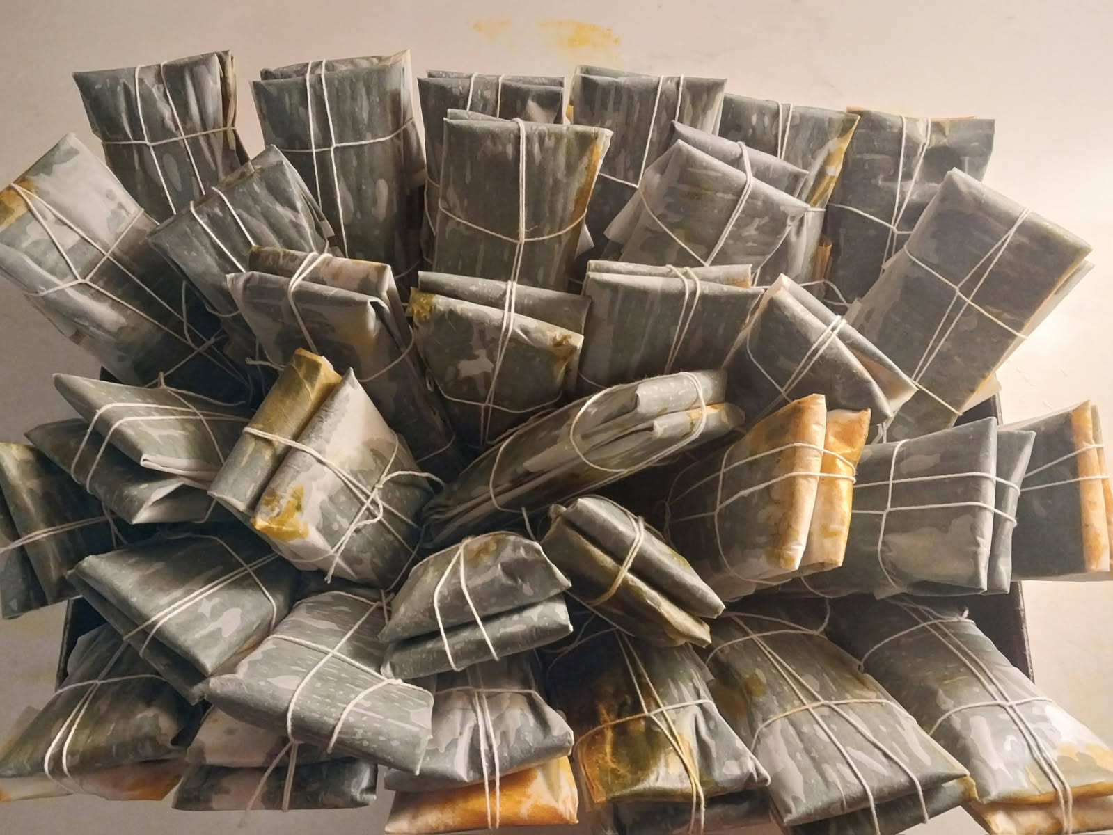 Dozens of handmade pasteles wrapped in banana leaf and tied by hand